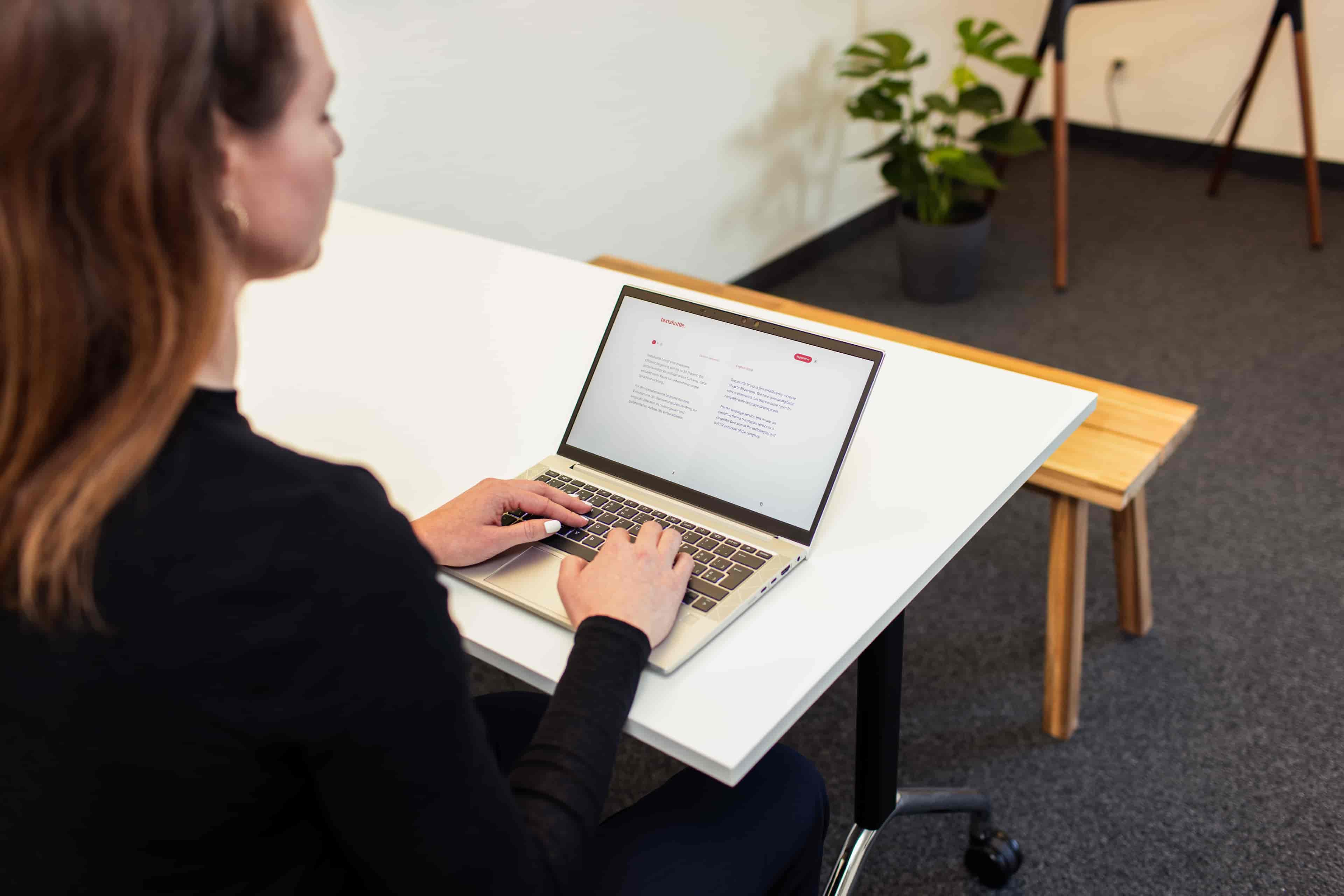 Woman typing on laptop, using Textshuttle Translation System